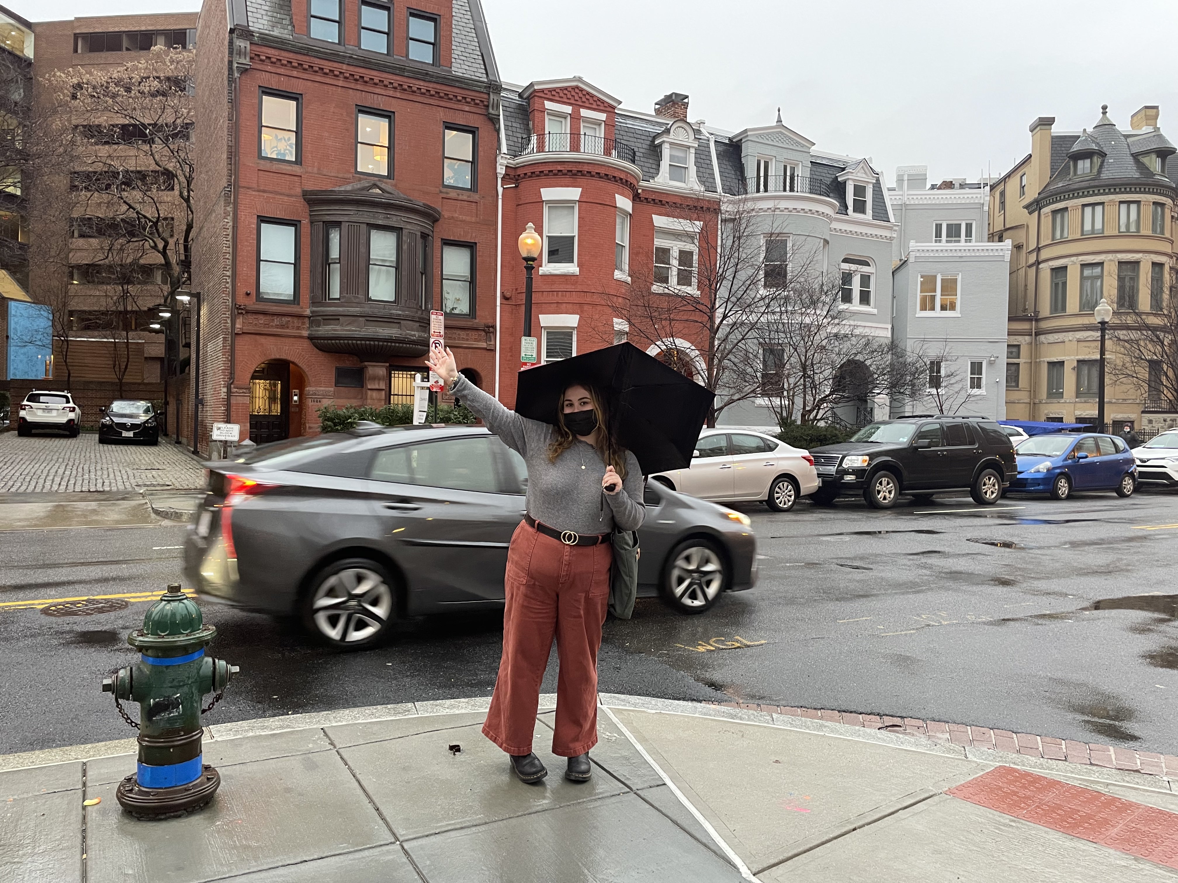 Photo of Hailey Dalton standing under an umbrella on a rainy sidewalk