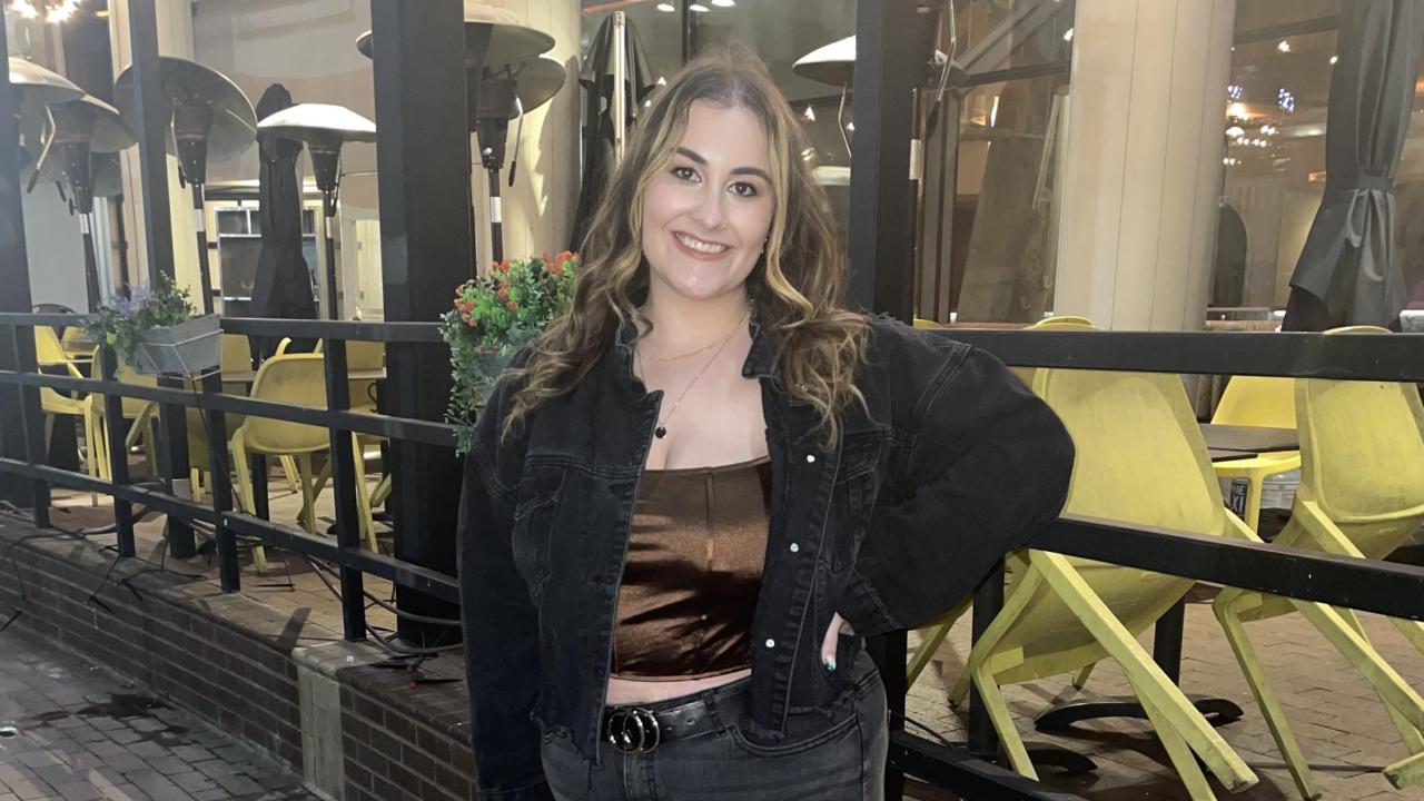 Photo of Hailey Dalton posing on the sidewalk in the evening. 