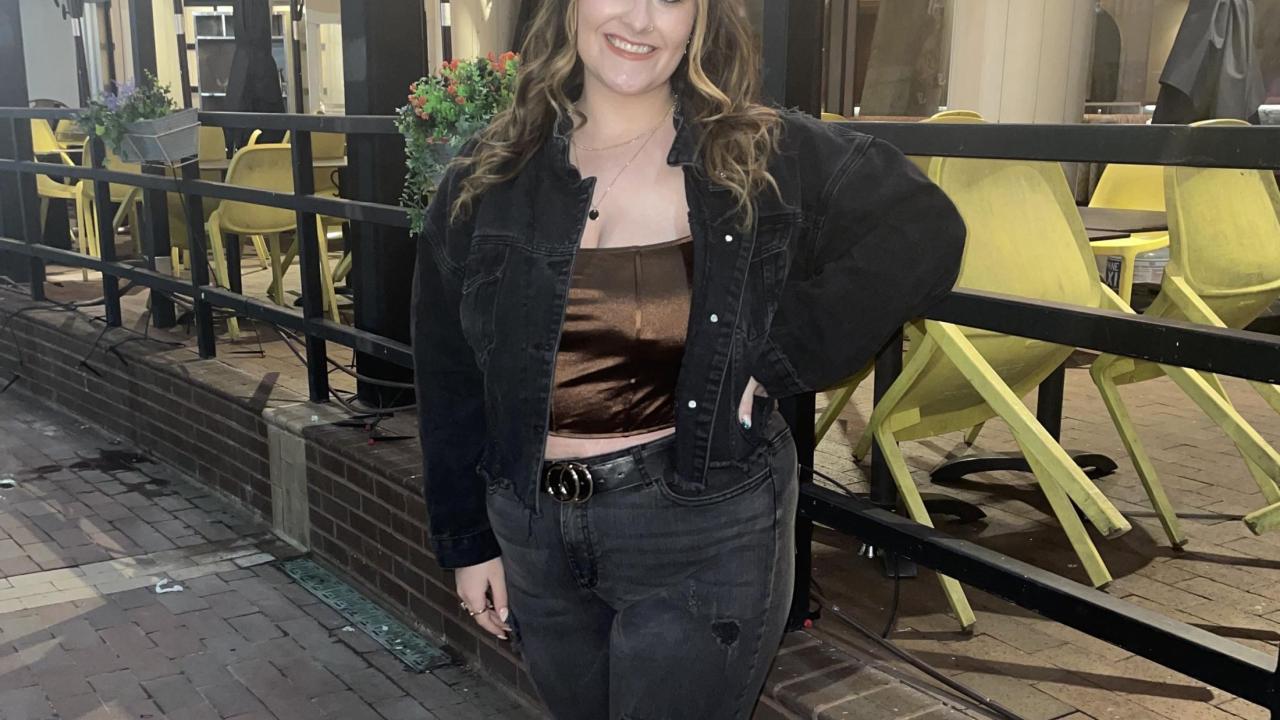 Photo of Hailey Dalton posing on the sidewalk in the evening. 