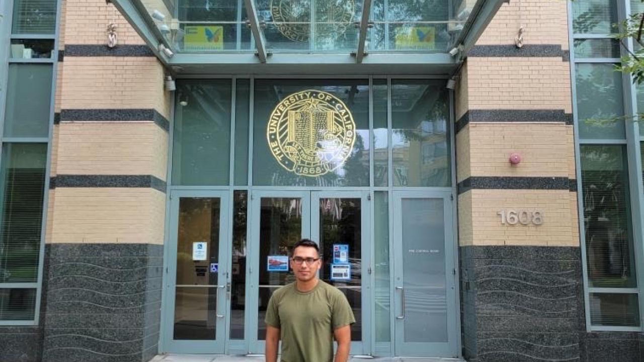 Photo of Christopher Rojas standing in front of a UC building