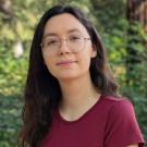 Image of Peer Advisor Natalie Crowley wearing red top and with a background of foliage and redwood trees.